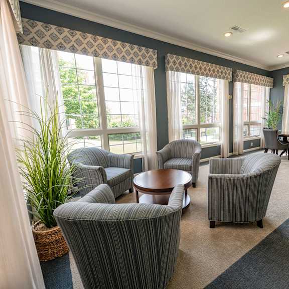 a living room with grey striped chairs and a round table.