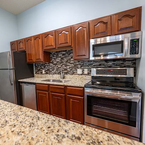 a kitchen with brown cabinets and a granite countertop.