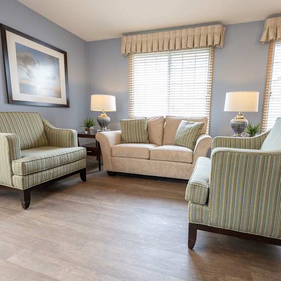 a living room with striped armchairs and a painting on the wall.