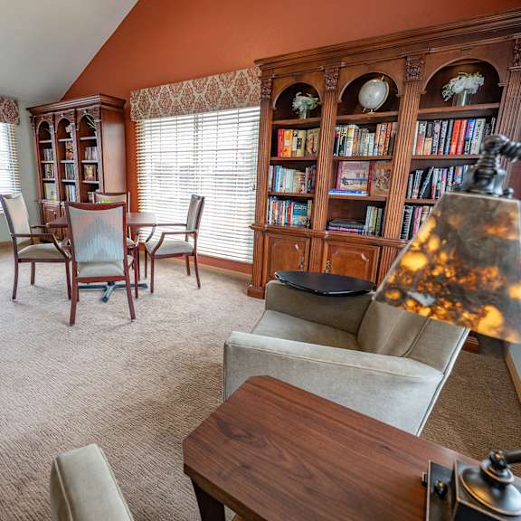 a living room with a brown carpet and a wooden bookcase.