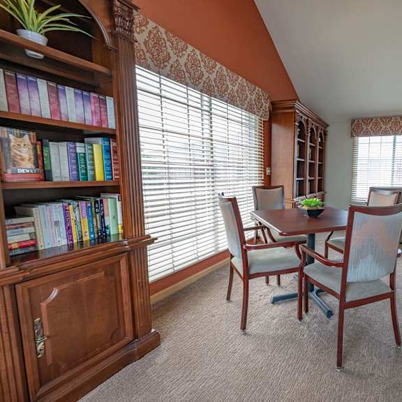 a room with a table, chairs, and a bookshelf.
