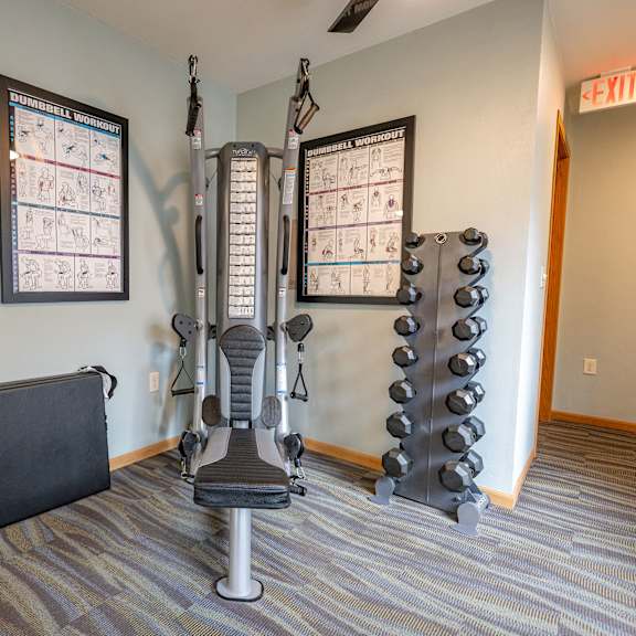 a gym room with a weight machine, a bench and a calendar on the wall.