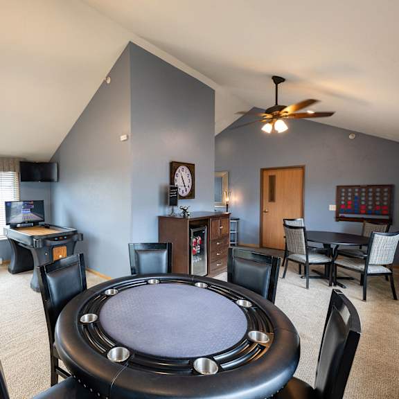 a poker table is surrounded by chairs in a room with a television and a clock on the wall.
