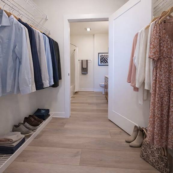 a hallway with clothes hanging on both sides and shoes on the floor.