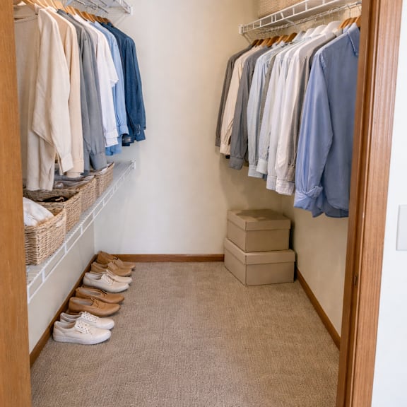 a small closet with clothes hanging and shoes on the floor.