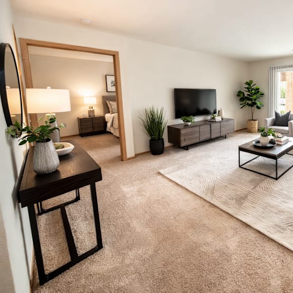 a well-lit living room with a large mirror, a flat-screen tv, and a variety of seating options.