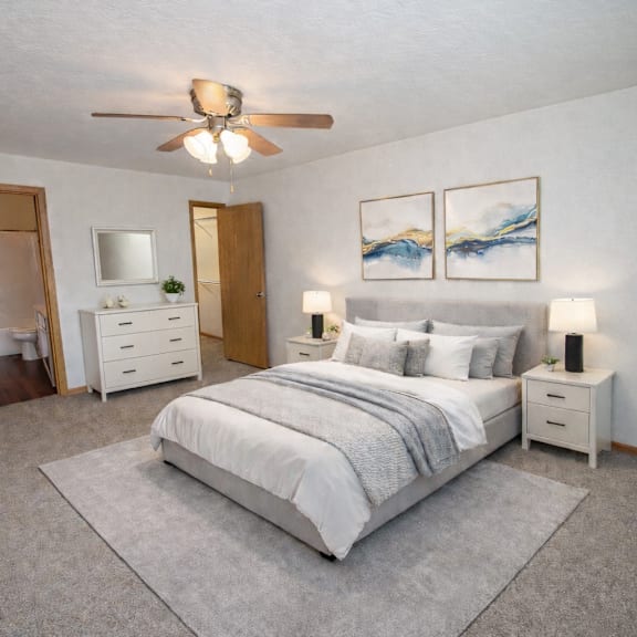 a bedroom with a large bed, a ceiling fan, and two nightstands.