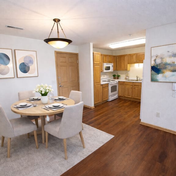 a dining room with a table set for two and a kitchen in the background.