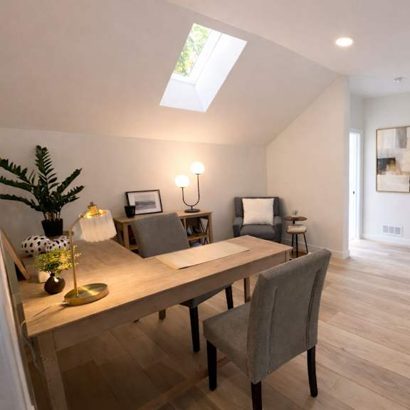 a room with a table and chairs and a skylight.