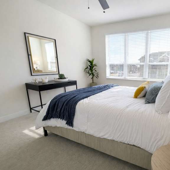 a bedroom with a bed, nightstand, and a window with blinds.