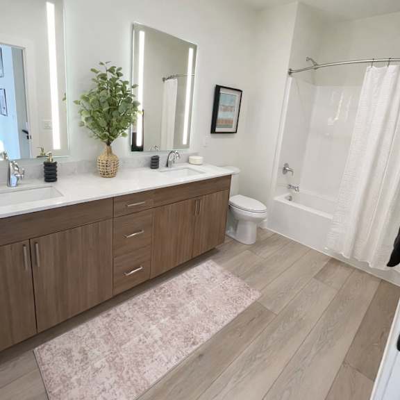 a bathroom with a white tub, sink, and a pink rug.
