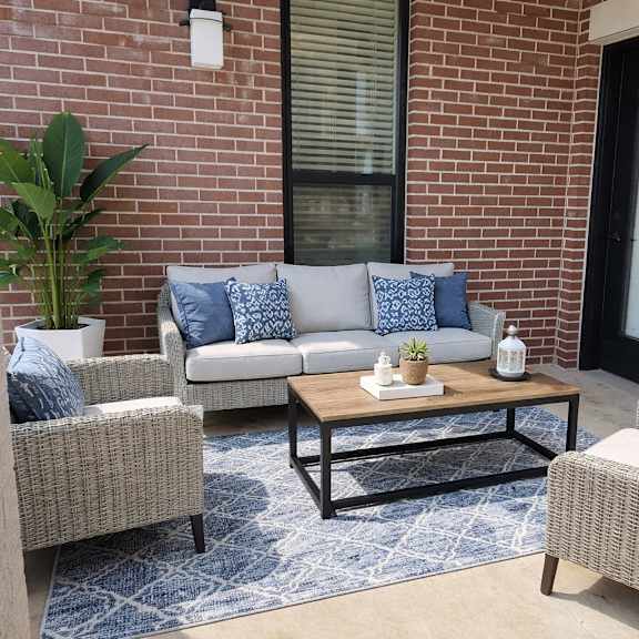 a patio with a sofa, two chairs, and a coffee table.