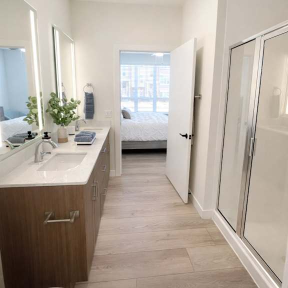 a bathroom with a toilet, sink, mirror, and a plant.