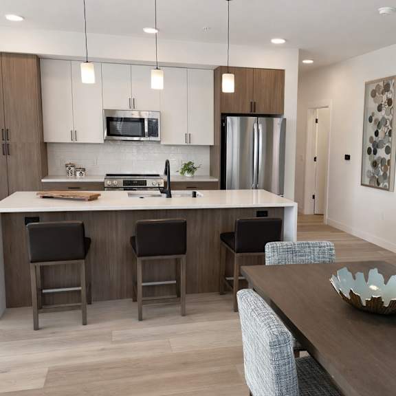 a modern kitchen with a wooden island and bar stools.