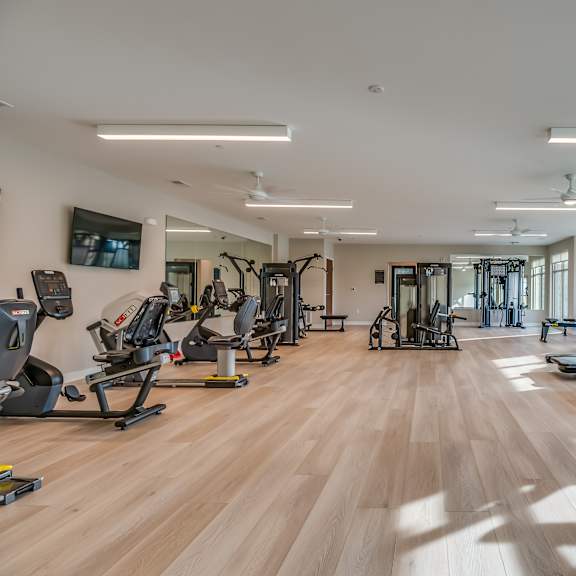 a gym with cardio equipment and weights on a wooden floor