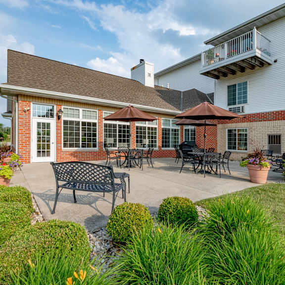 a patio with a table and chairs is surrounded by green plants.