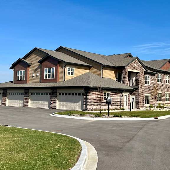 a large, two-story townhome building with attached garages a driveway in front.