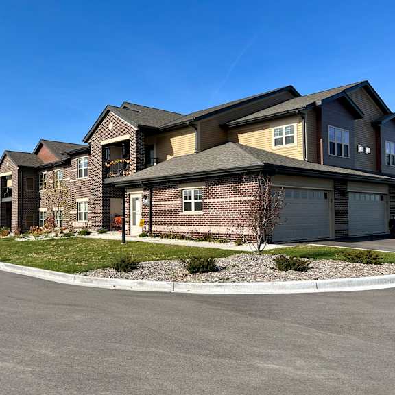 a row of townhomes and attached garages with a clear blue sky above them.