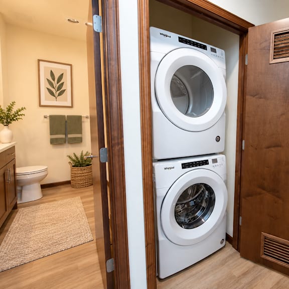 a white front loading washing machine is in a wooden door.