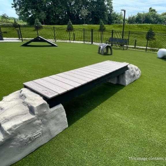 a playground with a slide, a rock, and a bench.