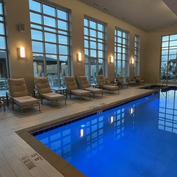 a large indoor swimming pool with sunlit windows and lounge chairs.