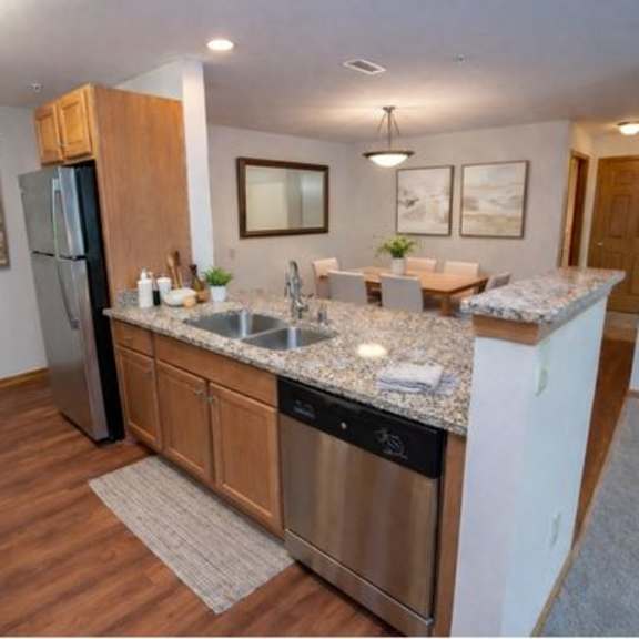 a kitchen with a refrigerator, sink, and cabinets.
