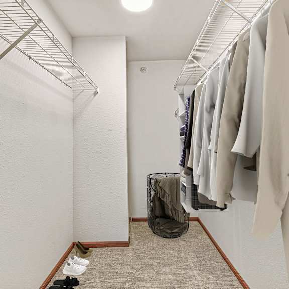 a hallway with clothes hanging on a rack and a pair of shoes on the floor.