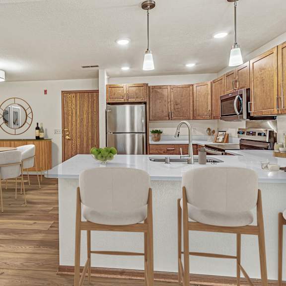 a kitchen with a white counter and brown chairs.