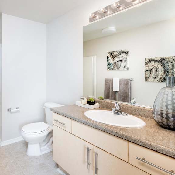 a bathroom with a toilet, sink, and mirror. at la jolla crossroads apartments, san diego, ca, 92122