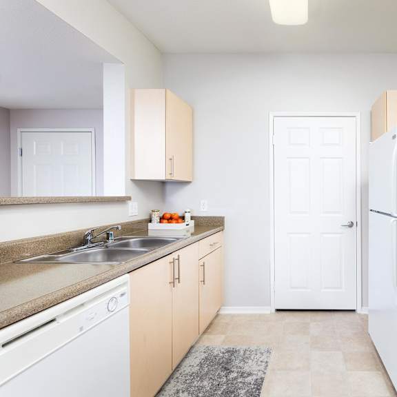 a kitchen with white appliances and beige cabinets. at la jolla crossroads apartments, san diego, 92122