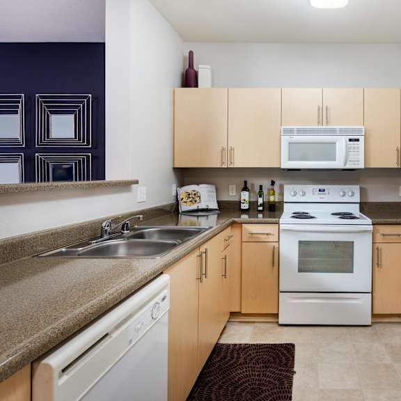 a kitchen with a white oven and refrigerator. at la jolla crossroads apartments, san diego