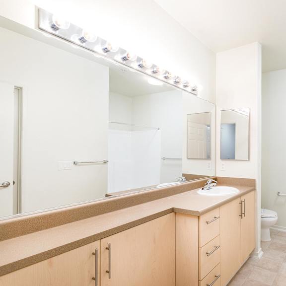 a bathroom with a sink, mirror, and toilet. at la jolla crossroads apartments, san diego, 92122
