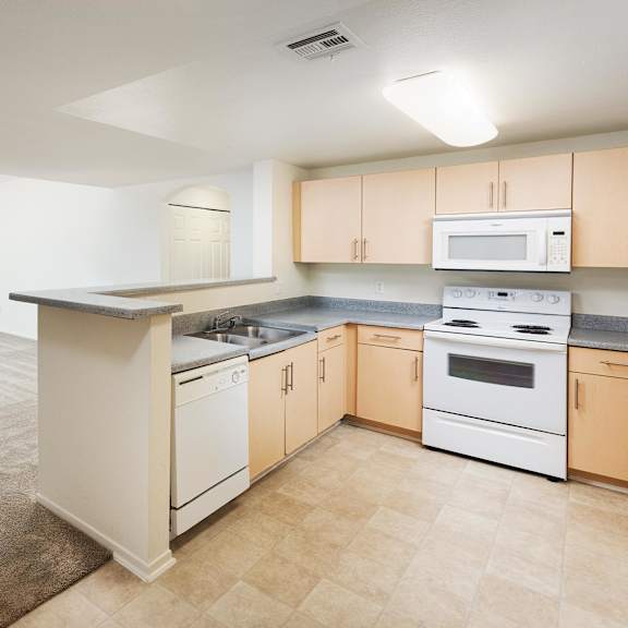 a kitchen with a white stove top oven and white dishwasher. at la jolla crossroads apartments, california