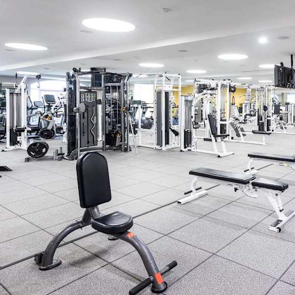 a spacious gym with a variety of equipment including treadmills, weight machines, and dumbbells. at la jolla crossroads apartments, san diego