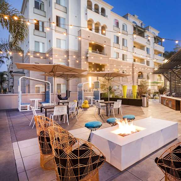 a patio with a fire pit surrounded by chairs and tables. at la jolla crossroads apartments, california
