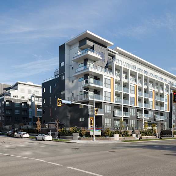 a modern multi-story building with balconies is situated on a street corner with traffic lights.