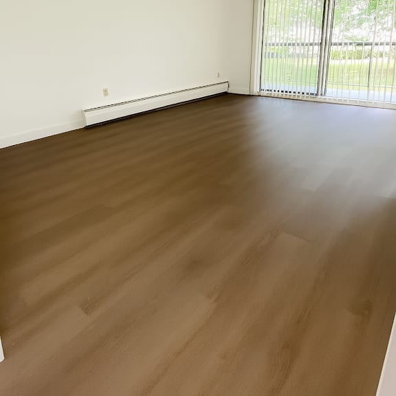 a room with wooden flooring and a window with blinds.