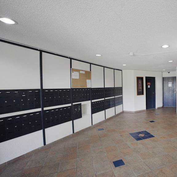 a hallway with a row of mailboxes on the left and a painting on the right.