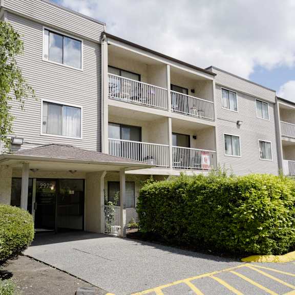apartment building with a parking lot in front.