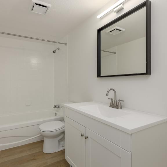 a white bathroom with a toilet, sink, and bathtub.