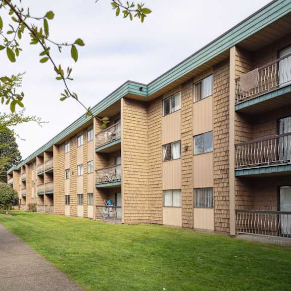 apartment building with a green roof and a tree in front of it.
