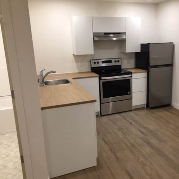a kitchen with a stove top oven, refrigerator, and sink.