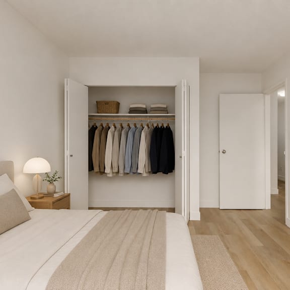 a bedroom with a large bed and a closet with clothes hanging.