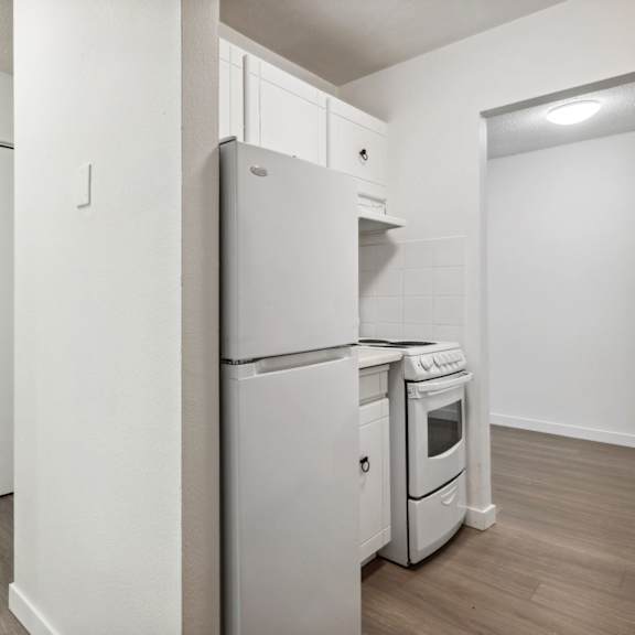 a white refrigerator and oven in a kitchen with white cabinets.