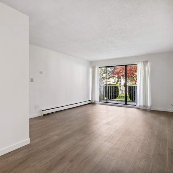 a spacious, empty room with wooden floors and white walls.