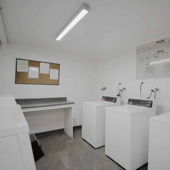 a laundromat with washers and dryers and a bulletin board on the wall.