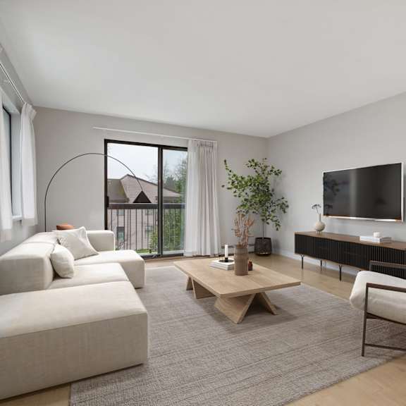 a living room with a white couch, a wooden coffee table, and a television.