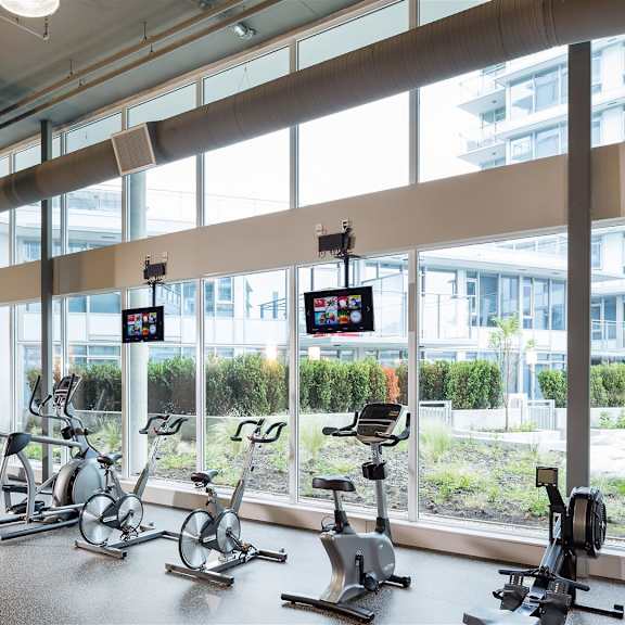 a gym with a row of stationary bikes and a view of the outside.