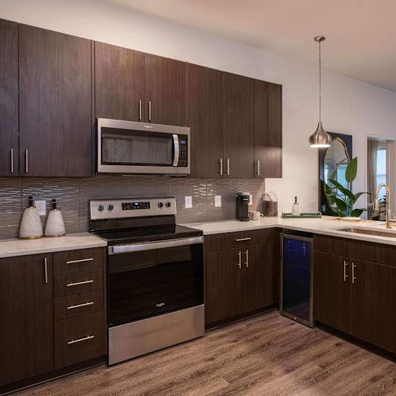 Thumbnail 7 of 8 Kitchen with dark wood cabinets, stainless steel appliances, and a built-in beverage cooler at The Apex at CityPlace, Overland Park, 66210