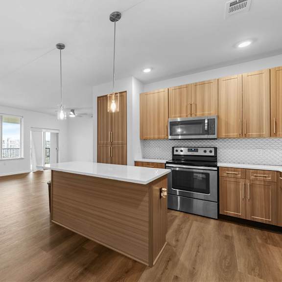 Thumbnail 2 of 6 A kitchen with wooden cabinets and a stainless steel oven.